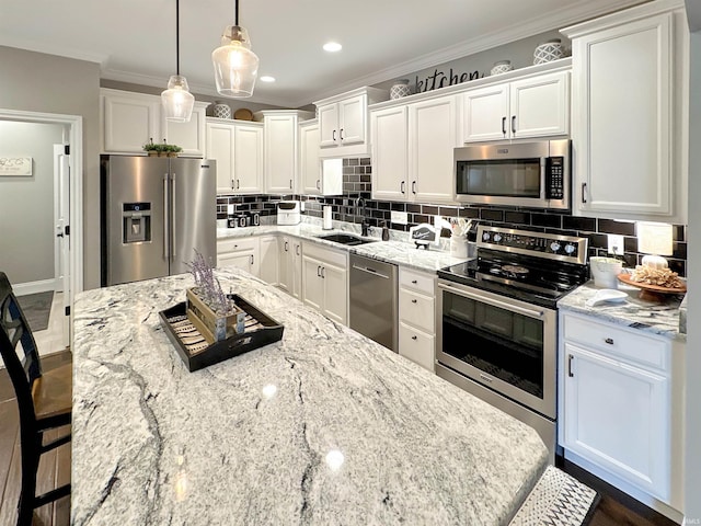 kitchen with ornamental molding, a sink, stainless steel appliances, white cabinets, and decorative backsplash