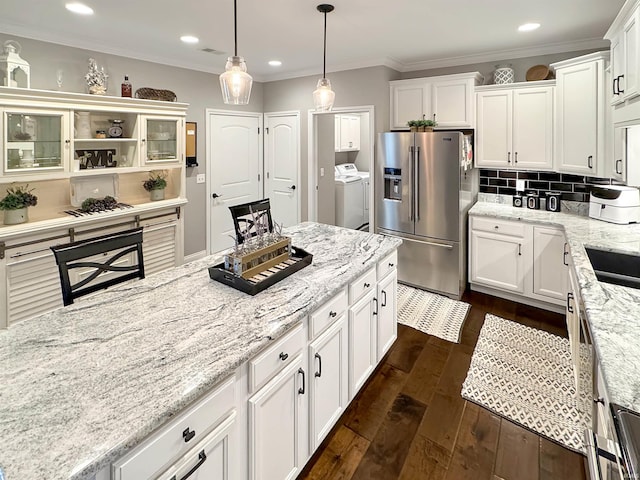 kitchen with ornamental molding, backsplash, washing machine and dryer, stainless steel fridge with ice dispenser, and dark wood-style flooring