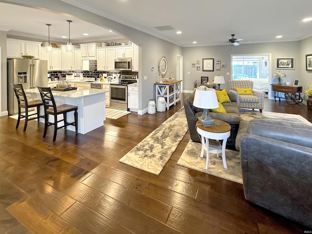 living room featuring dark wood-type flooring, a ceiling fan, recessed lighting, crown molding, and baseboards