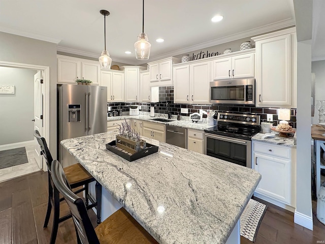 kitchen with decorative backsplash, white cabinets, appliances with stainless steel finishes, and ornamental molding