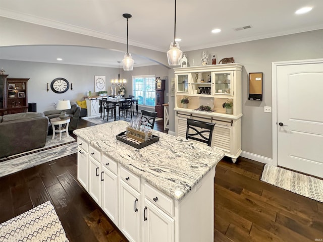 kitchen with visible vents, decorative light fixtures, ornamental molding, light stone counters, and dark wood-style floors