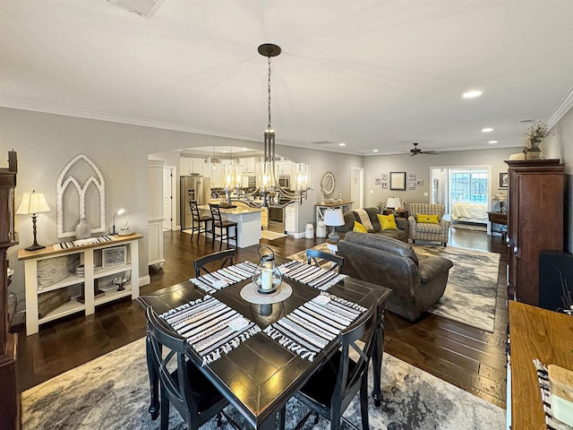 dining space with baseboards, recessed lighting, ornamental molding, dark wood-type flooring, and ceiling fan with notable chandelier