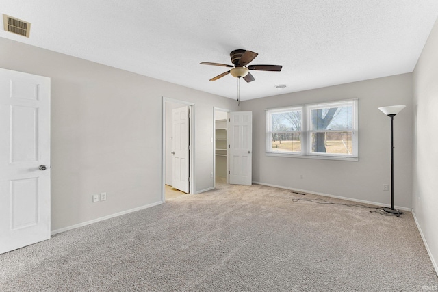 unfurnished bedroom featuring visible vents, carpet floors, a textured ceiling, and baseboards