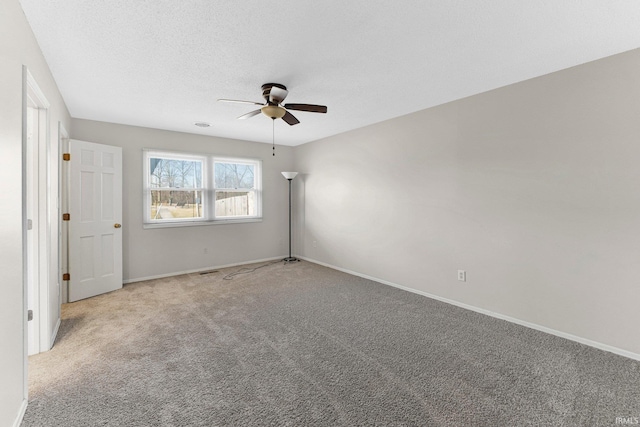 carpeted spare room with ceiling fan, baseboards, and a textured ceiling