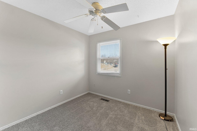 carpeted empty room with a textured ceiling, baseboards, visible vents, and ceiling fan