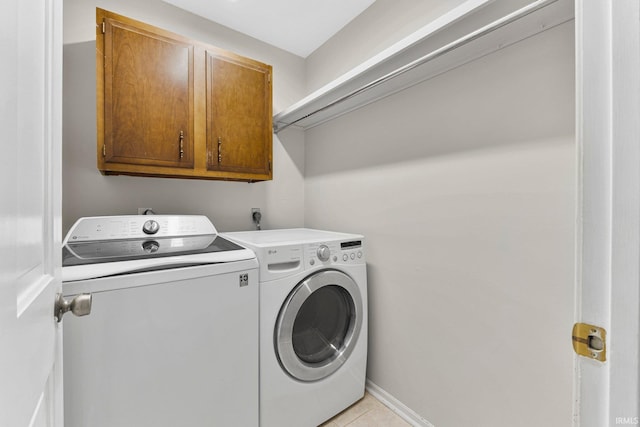 clothes washing area with washer and dryer, light tile patterned floors, cabinet space, and baseboards