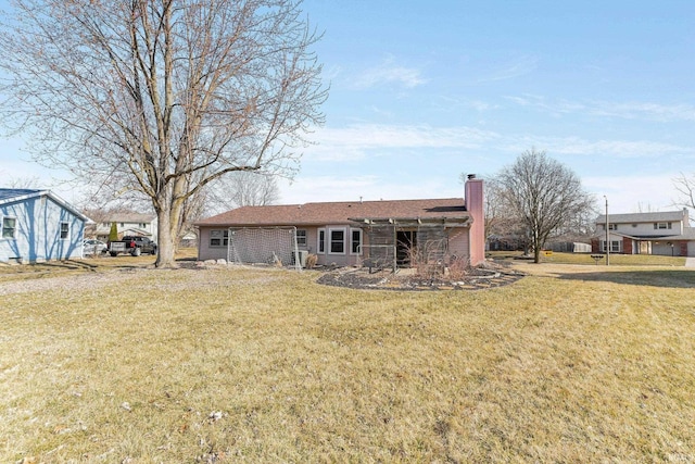 rear view of house featuring a chimney and a yard