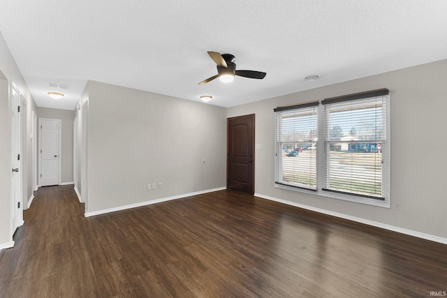 spare room featuring visible vents, baseboards, dark wood-type flooring, and ceiling fan