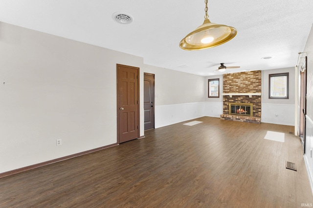 unfurnished living room featuring visible vents, a fireplace, and wood finished floors