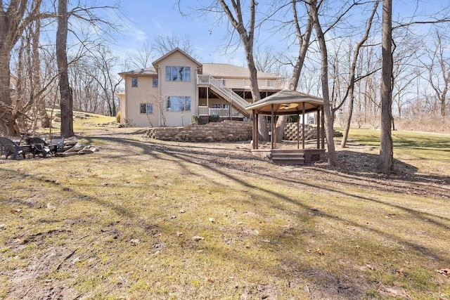 rear view of property with stairs and a lawn