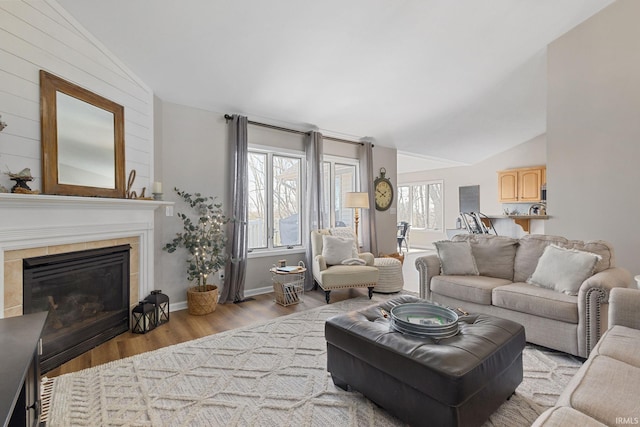 living area featuring a fireplace, baseboards, lofted ceiling, and wood finished floors