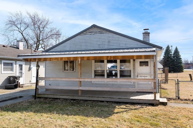 back of property featuring metal roof, fence, a chimney, and a gate