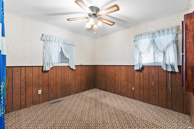 unfurnished room featuring wooden walls, wainscoting, and wallpapered walls