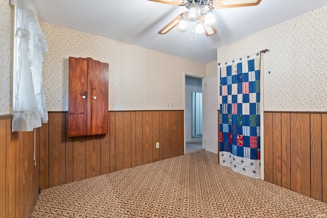 spare room featuring wallpapered walls, wooden walls, and wainscoting