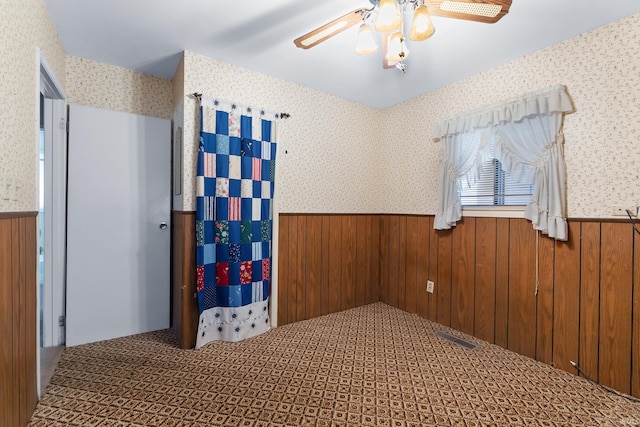 unfurnished room with wallpapered walls, wood walls, and wainscoting