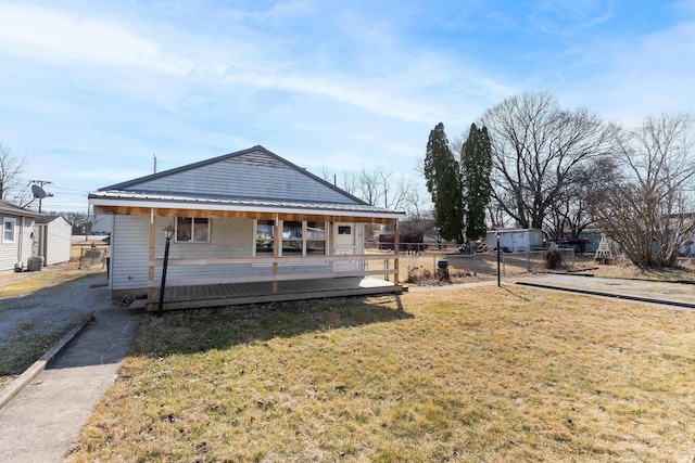 rear view of house with a lawn, metal roof, and fence