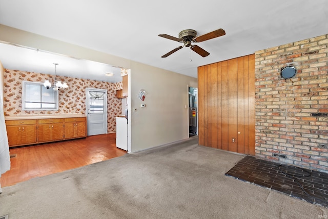 unfurnished living room with ceiling fan with notable chandelier and light colored carpet