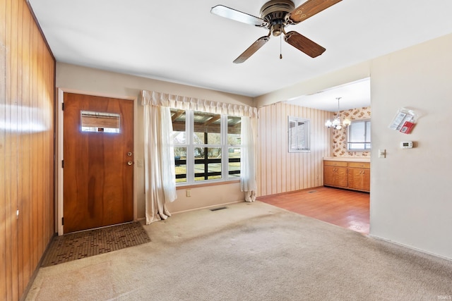 foyer with visible vents, ceiling fan with notable chandelier, and carpet