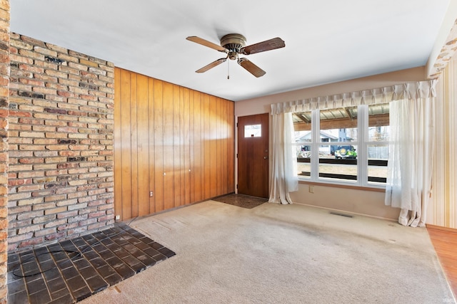 interior space with visible vents, wood walls, and a ceiling fan