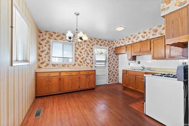 kitchen featuring visible vents, wallpapered walls, a sink, light countertops, and white gas range oven