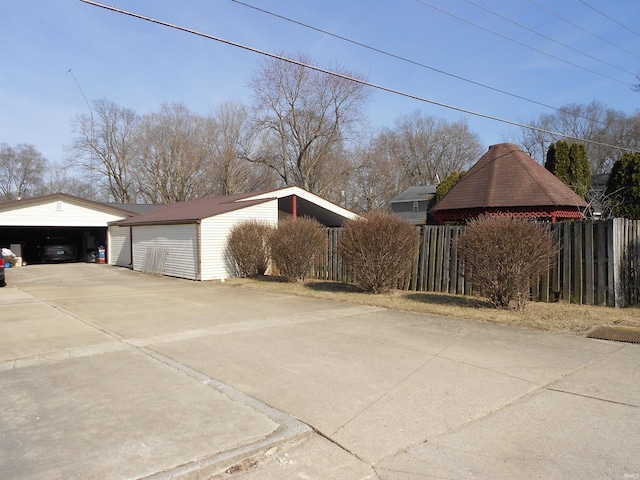 view of side of property featuring an outdoor structure, fence, and a detached garage