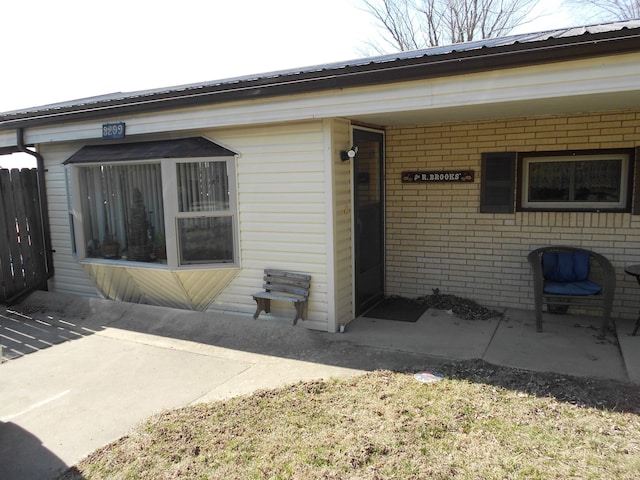 view of exterior entry featuring brick siding and metal roof