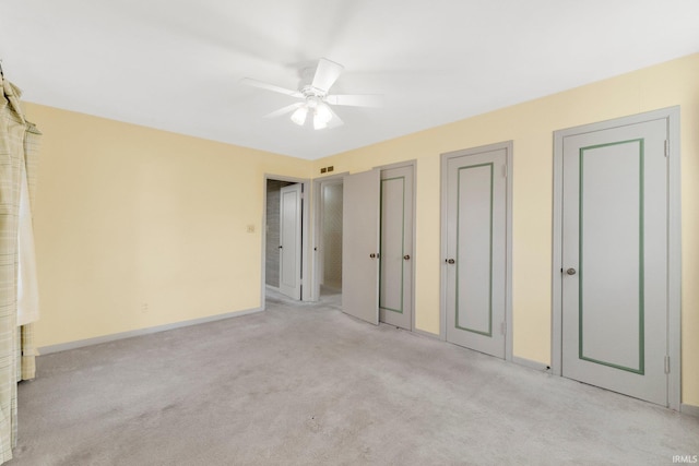 unfurnished bedroom with visible vents, multiple closets, light colored carpet, and baseboards