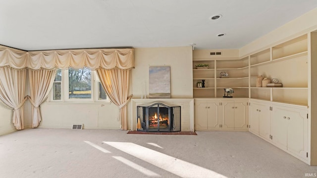 unfurnished living room featuring a brick fireplace, recessed lighting, light colored carpet, and visible vents