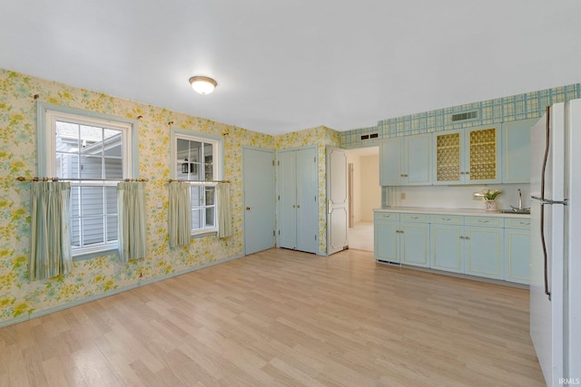 spare room with wallpapered walls, light wood-style floors, visible vents, and baseboards