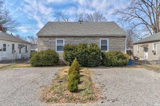 view of front of home featuring fence, driveway, and a shingled roof