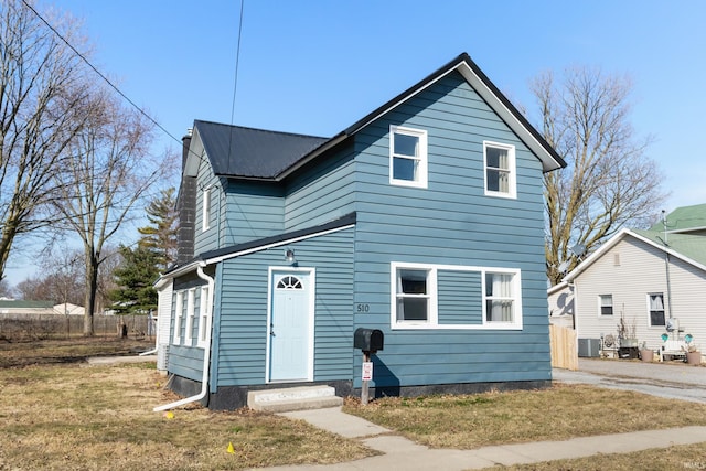 traditional home featuring metal roof, central air condition unit, and a front yard