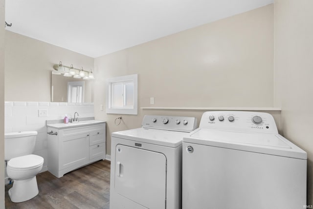 laundry area featuring dark wood-type flooring, a sink, washing machine and dryer, tile walls, and laundry area