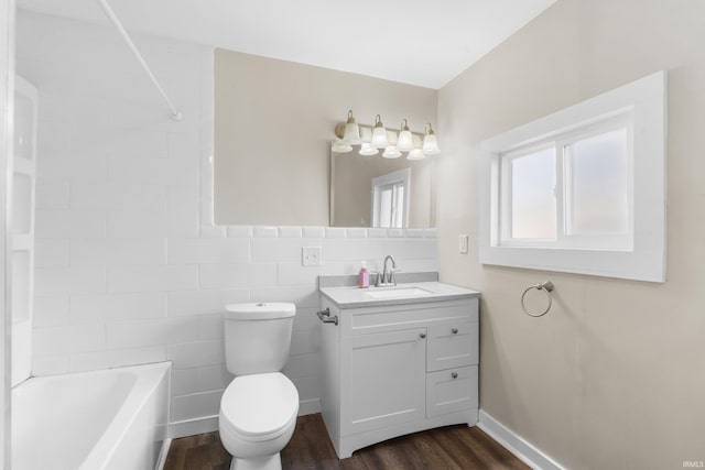 bathroom with baseboards, toilet, vanity, wood finished floors, and tile walls