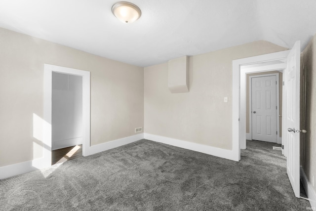 empty room featuring visible vents, baseboards, carpet, and vaulted ceiling