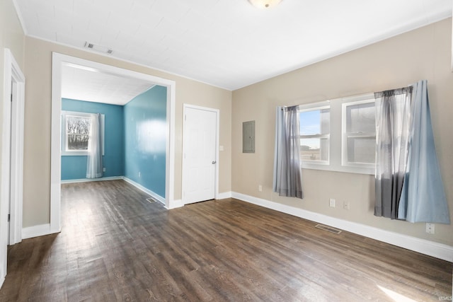 spare room with electric panel, visible vents, baseboards, and dark wood finished floors