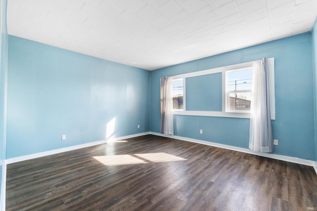 spare room featuring baseboards and wood finished floors