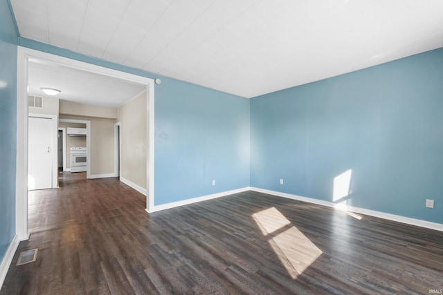 spare room with visible vents, dark wood-style floors, and baseboards