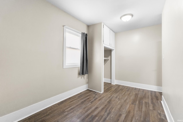 unfurnished bedroom with baseboards and dark wood finished floors