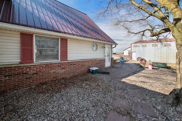 view of side of home with metal roof, brick siding, and a patio area