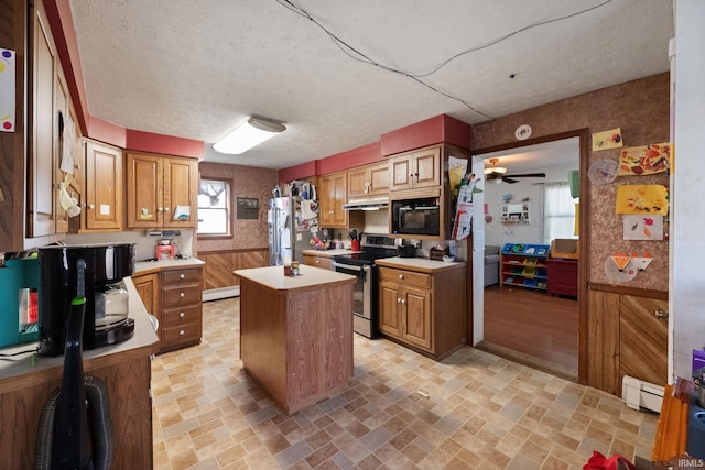 kitchen with a wainscoted wall, under cabinet range hood, a center island, stainless steel appliances, and light countertops