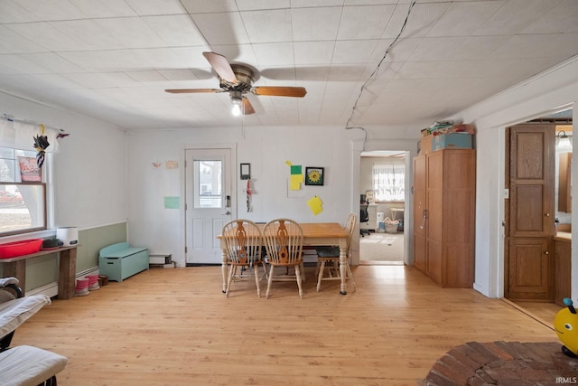 dining area with light wood-style flooring, a baseboard radiator, and ceiling fan