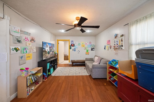 playroom with a textured ceiling, wood finished floors, and a ceiling fan