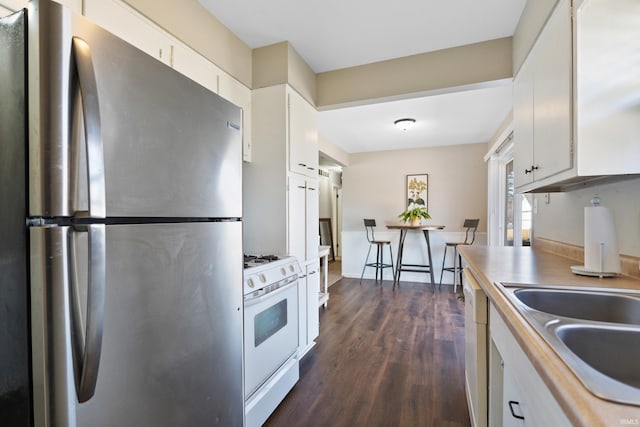 kitchen featuring dark wood-type flooring, light countertops, white appliances, white cabinetry, and a sink