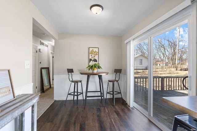 dining space featuring dark wood-style floors, visible vents, and baseboards