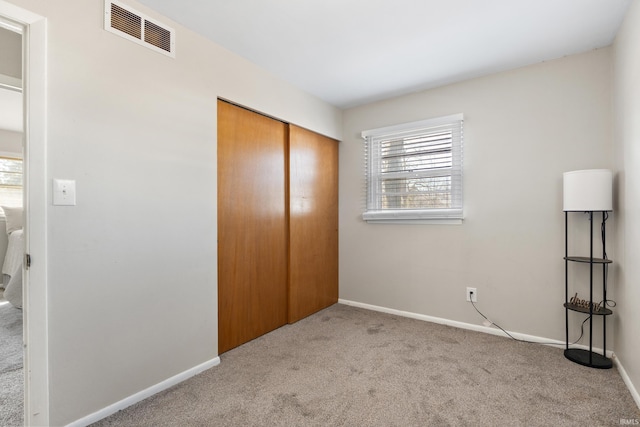 unfurnished bedroom with carpet, visible vents, a closet, and baseboards