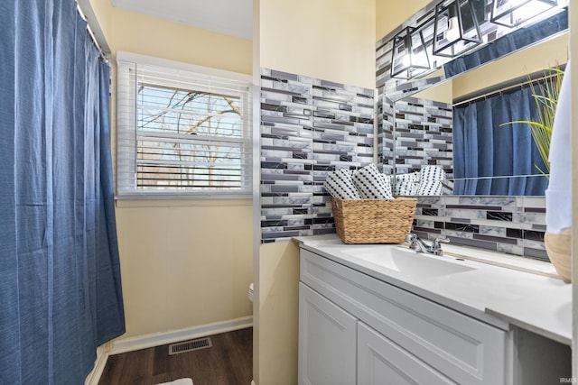 bathroom featuring tasteful backsplash, baseboards, toilet, wood finished floors, and vanity