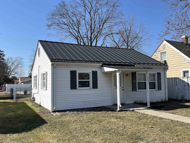 bungalow-style home featuring metal roof, a standing seam roof, a front yard, and fence