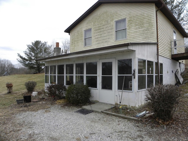 back of house with a chimney and a sunroom