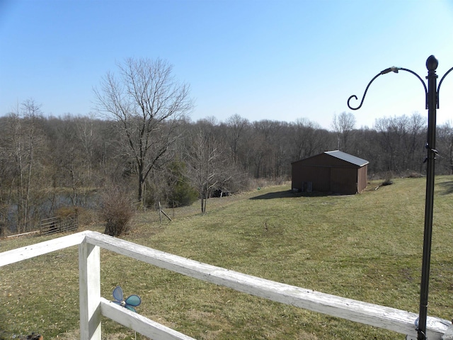 view of yard with an outbuilding and a view of trees