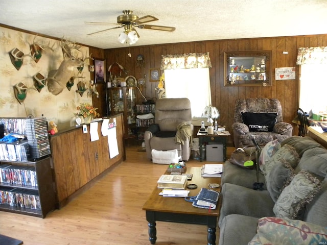 living room with plenty of natural light, a ceiling fan, light wood finished floors, and a textured ceiling